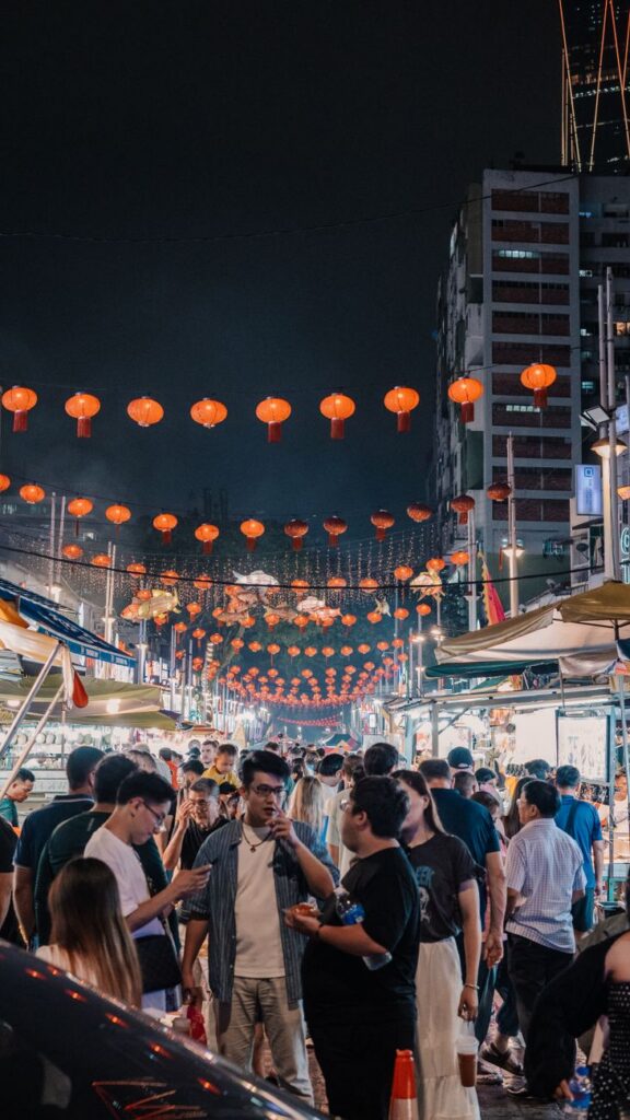 people walking through an outdoor market at night