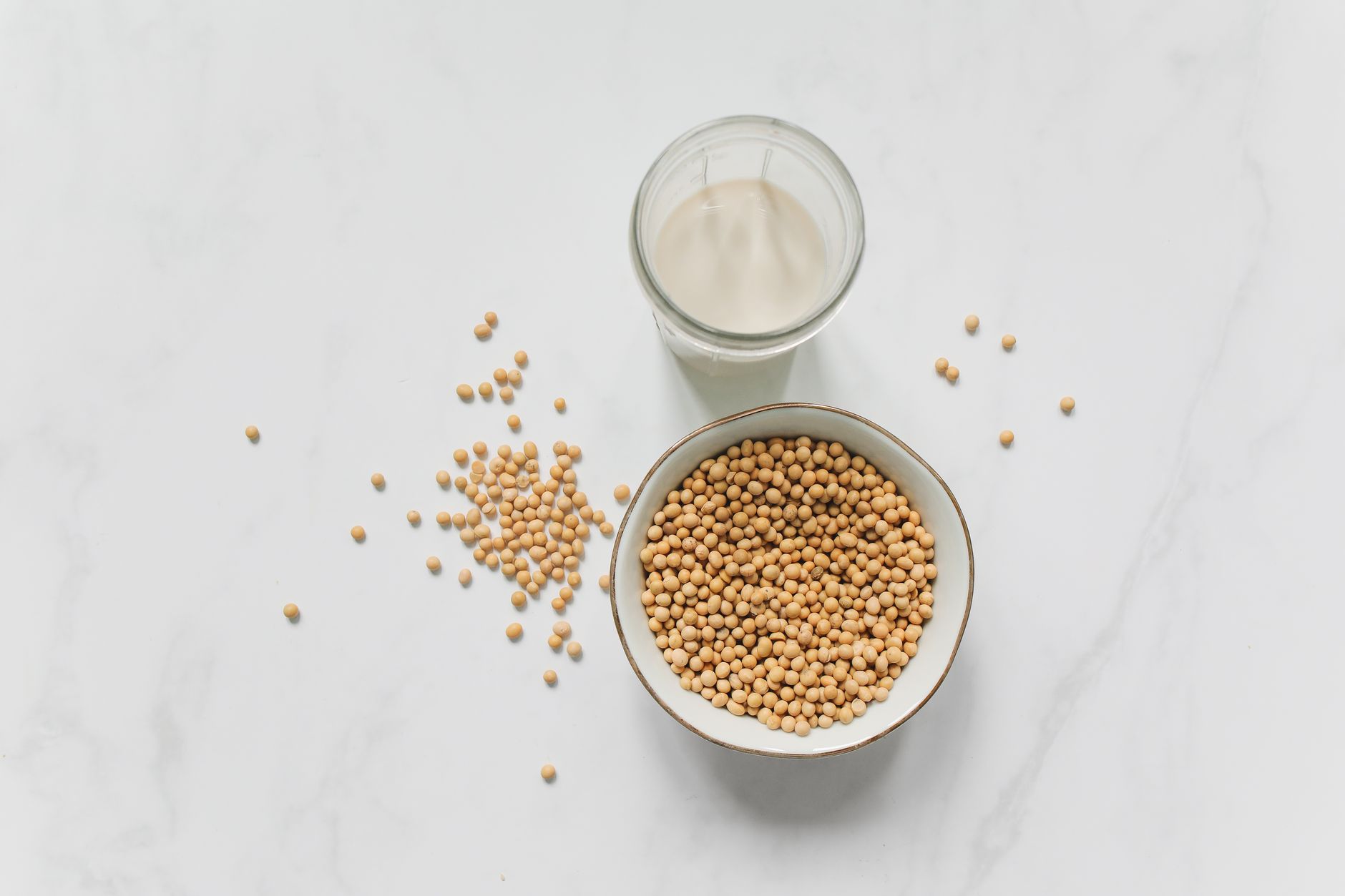 top view photo of soybeans on bowl near drinking glass with soy milk